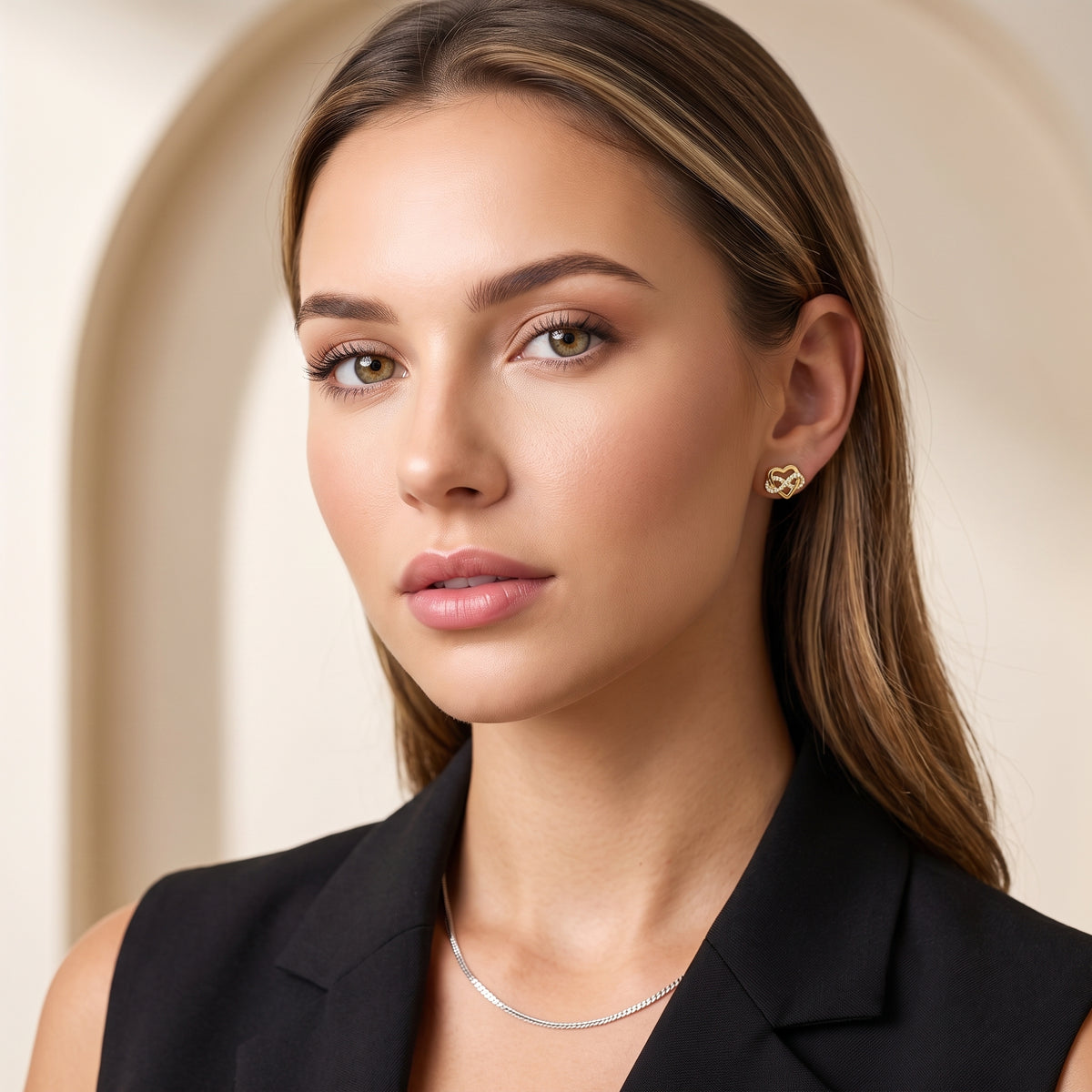 Elegancka stylizacja wieczorowa z pozłacanymi kolczykami serce, ciemna marynarka i odsłonięta szyja